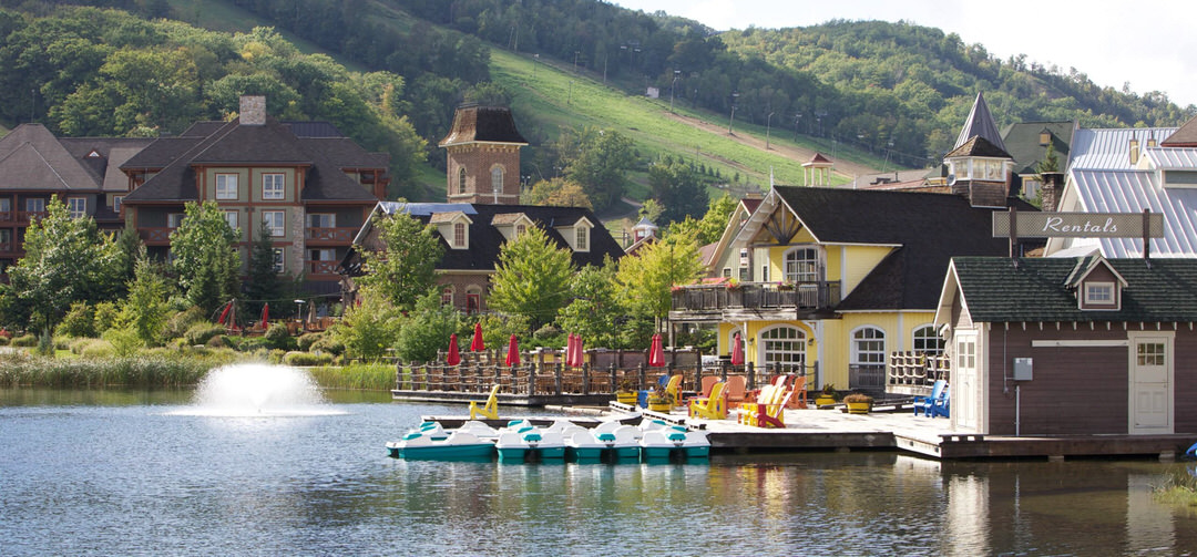 Several restaurants and accommodations with floating docks surrounding a body of water with paddle boats docked.