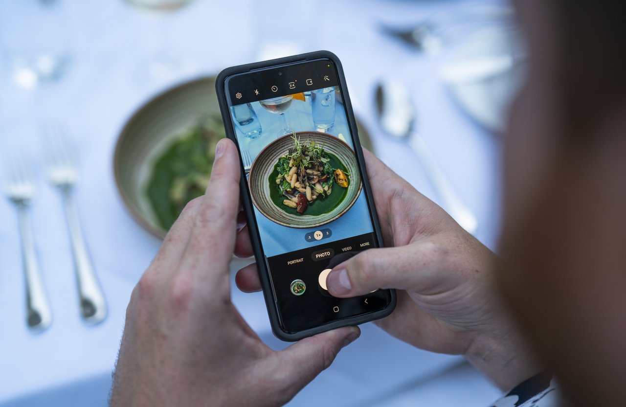  Un homme prend une photo d'un délicieux plat de cuisine à l'aide de son téléphone portable.