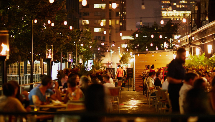 Guests enjoy evening al fresco dining on an outdoor patio under twinkling lights.