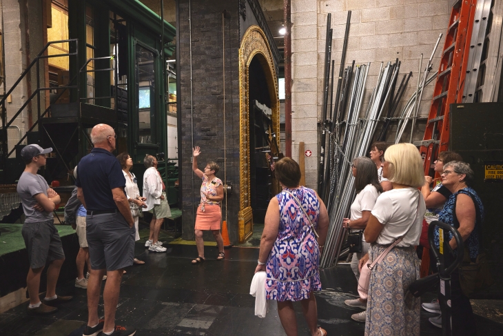 A woman gives a backstage tour to a group of people at the Shaw Festival Theatre. 