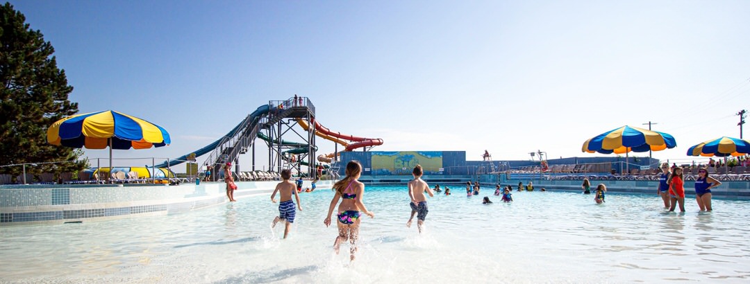 Children in swimming clothes are having fun in the pool as lifeguards watch the kids