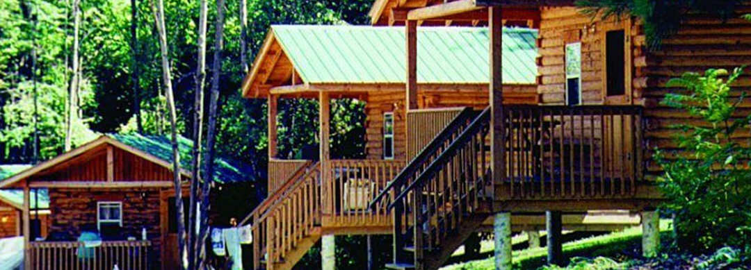 Raised wooden cabins are lined side-by-side, surrounded by trees