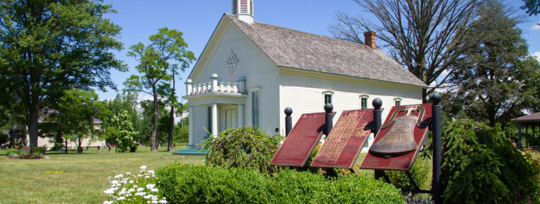 A plaque with historical information introduces the landmark and house surrounded by trees