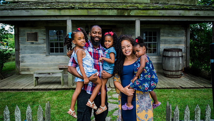 A family of five in front of a historic home