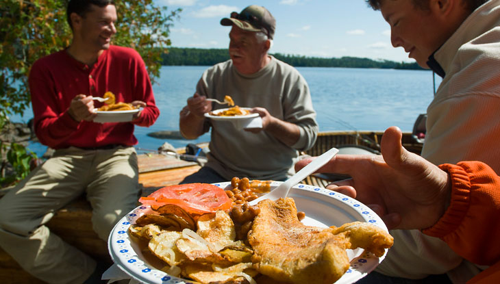 A group of anglers enjoy a shore lunch.