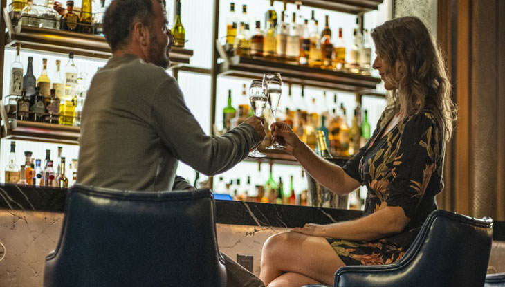 A couple share a toast at a bar.