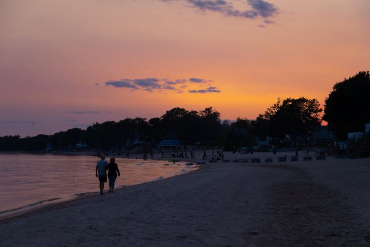 A couple walking on a beach at sunset. 