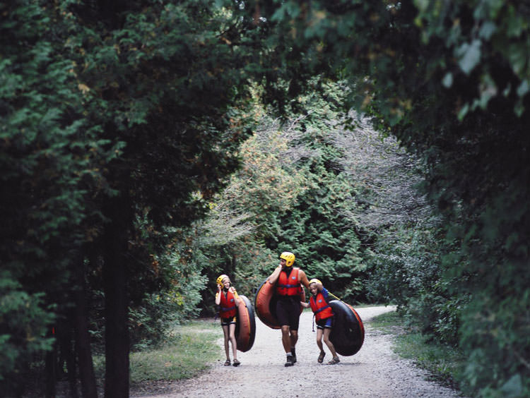 Homme adulte avec deux enfants, portant tous des chambres à air, portant des casques et des gilets de sauvetage