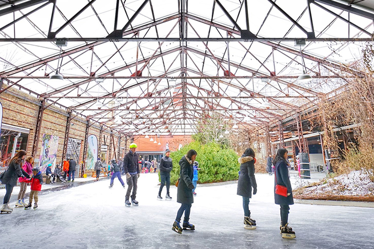 Des personnes patinent autour de parterres de jardin enneigés à Evergreen Brick Works.