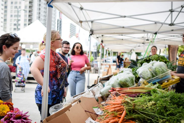 Un groupe de personnes examine les produits à un marché fermier. 