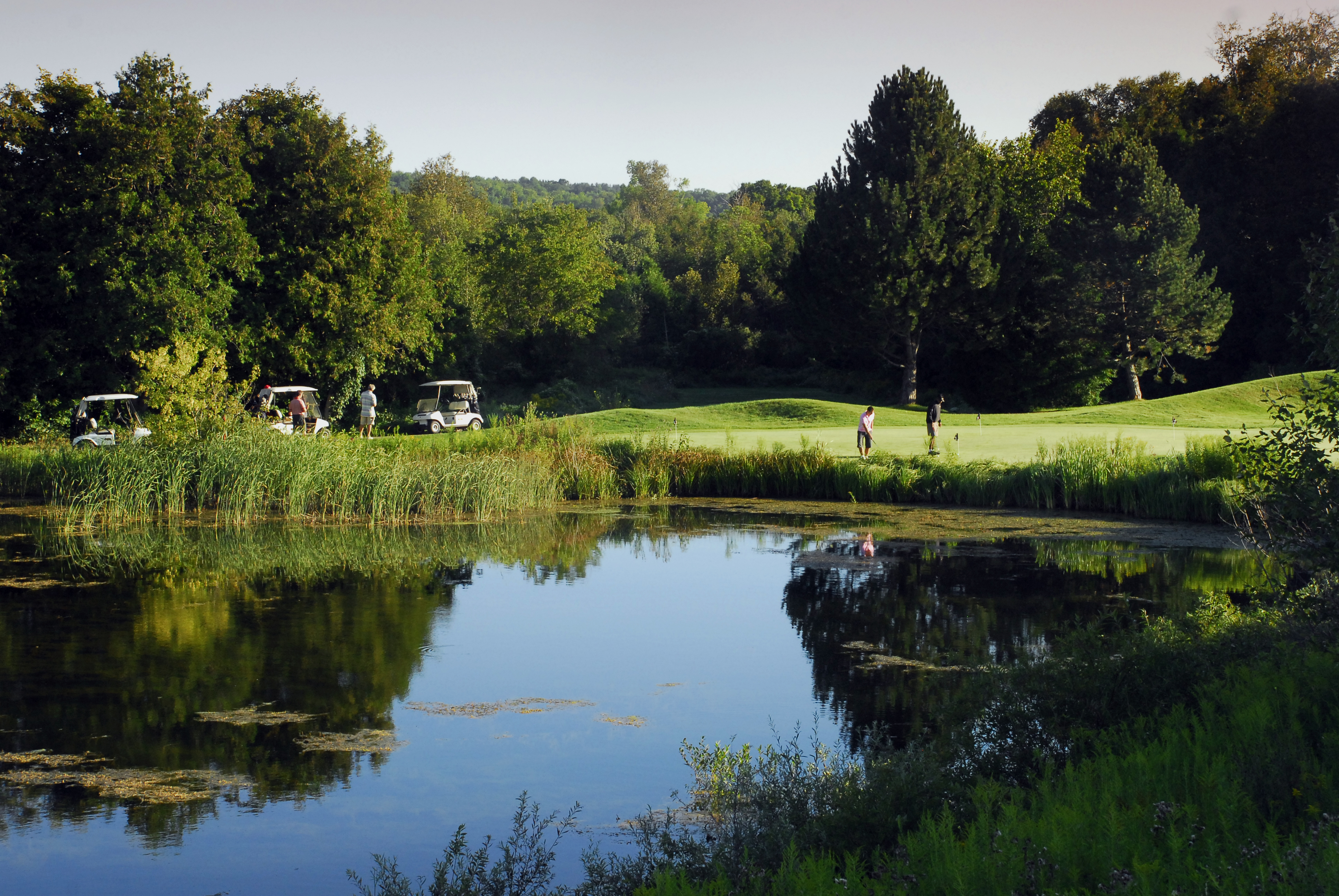 Golfers play by a pond.