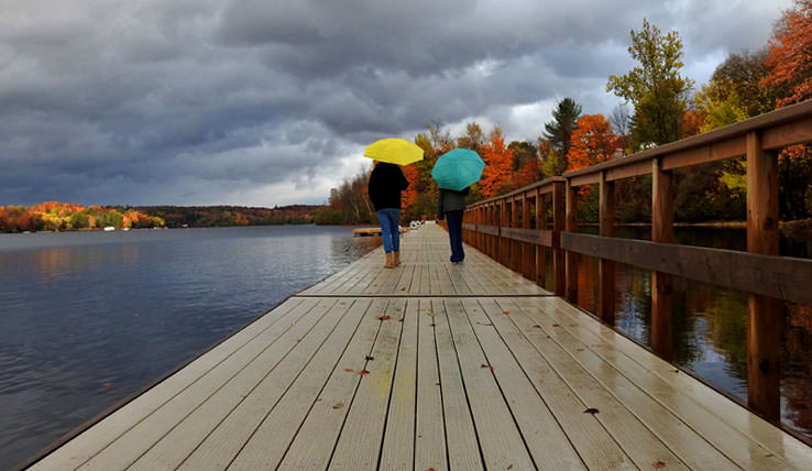 Deux femmes marchant sur une promenade portant des parapluies.