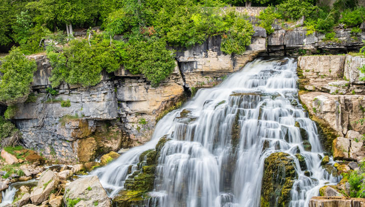 A scenic waterfalls surrounded by dramatic rock, cliff and forest.