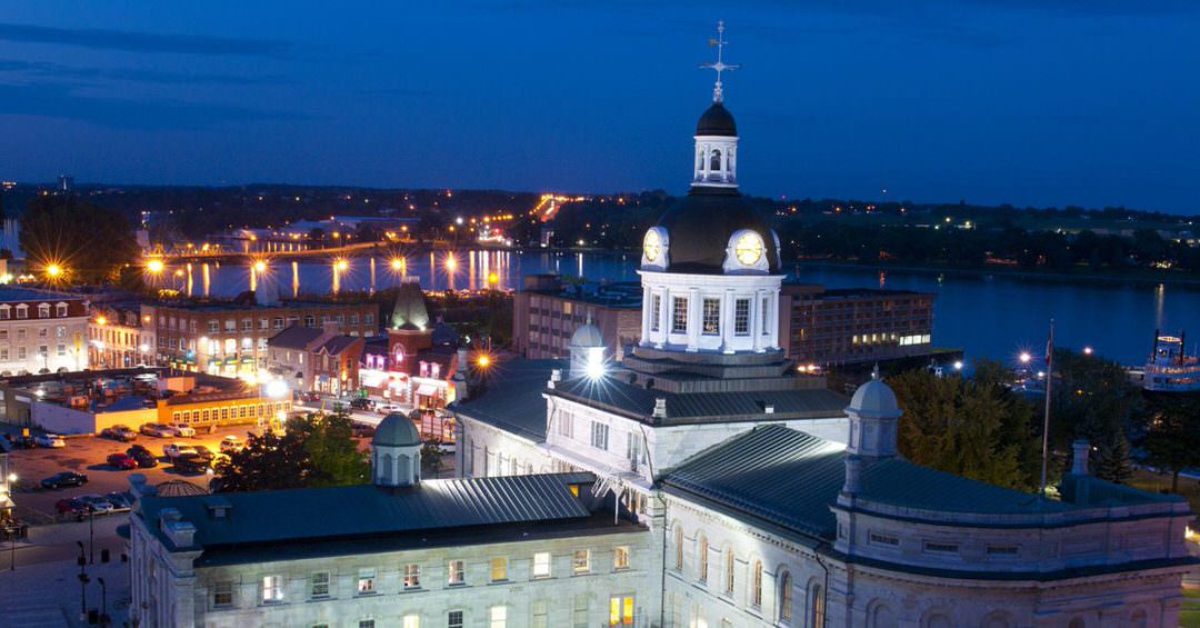 Historic buildings by the waterfront are lit by street lights during the evening.