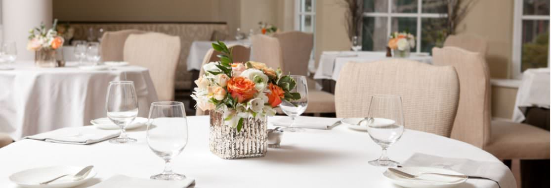 Salle à manger Langdon Hall, chaises autour de tables rondes en lin blanc, décorées de pièces centrales de fleurs