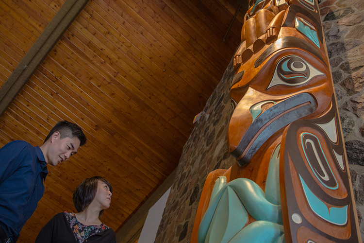 A couple admire a large totem sculpture. 