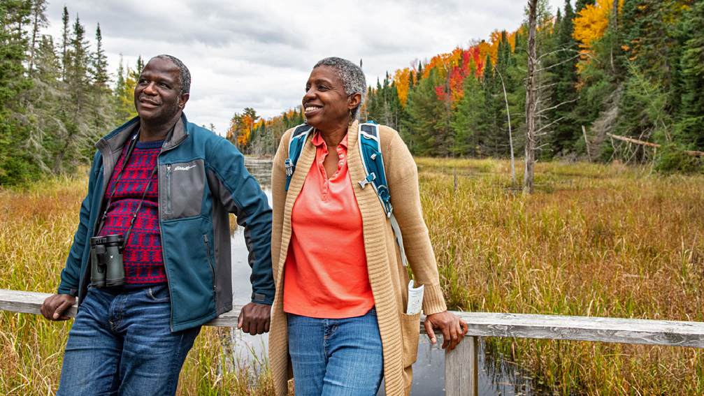 Una pareja disfrutando de los colores del otoño y observando aves en un parque.