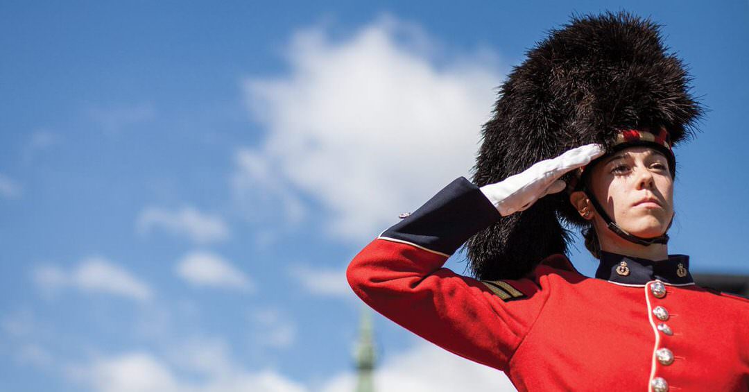 A Mountie saluting in front of the parliament building.