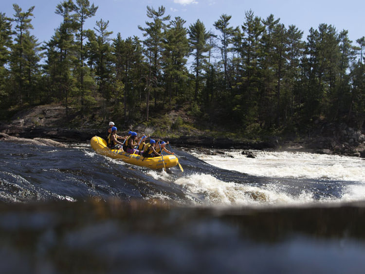 Eine Gruppe von Menschen in einem gelben Floß beim Wildwasserrafting einen Fluss hinunter