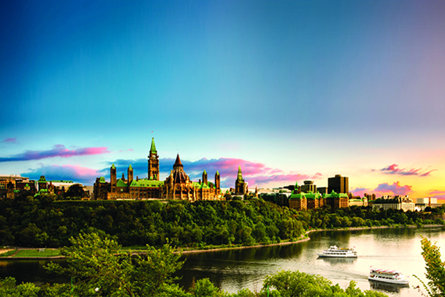 View of Parliament buildings and the Ottawa River with a bright blue sky