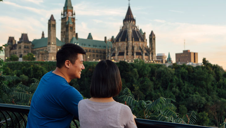 A couple sit in front of the Ottawa sign in downtown Ottawa.