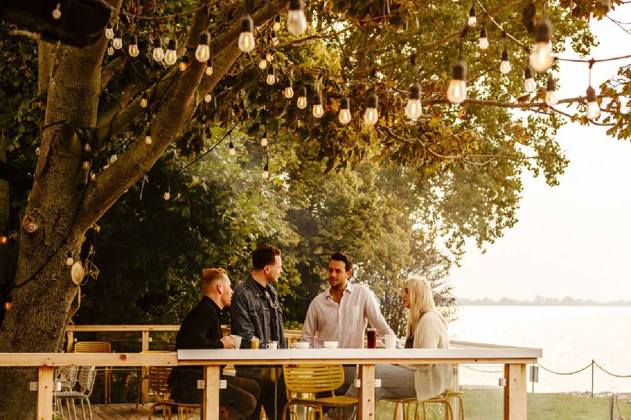 A group of people enjoying drinks on a patio by Lake Ontario.