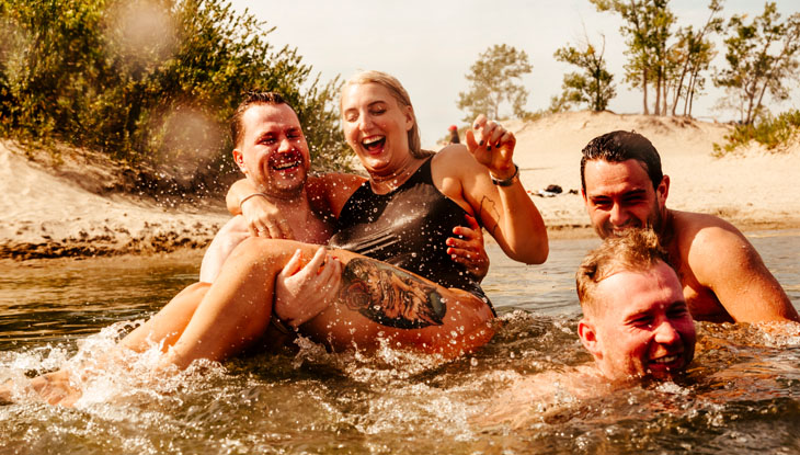 Four adults playing in the water at Sandbanks beach in Prince Edward County.