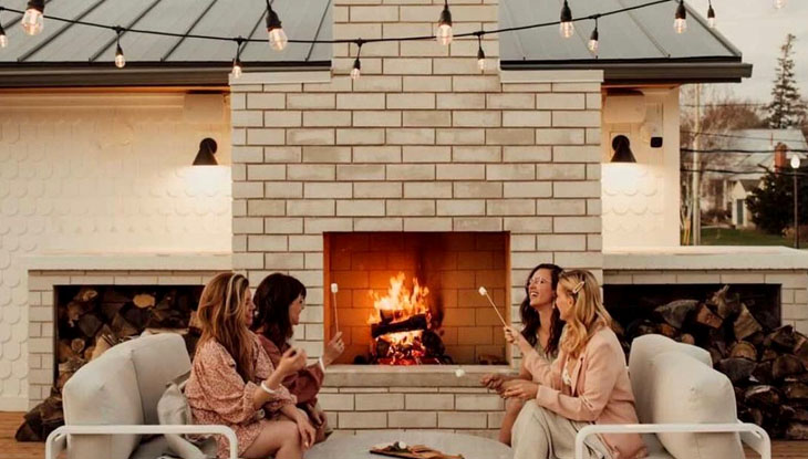 Four women socializing in front of a fireplace