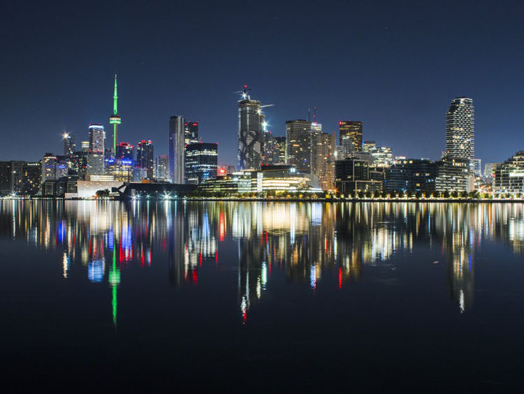 Toronto skyline lit up at night and reflecting off the water