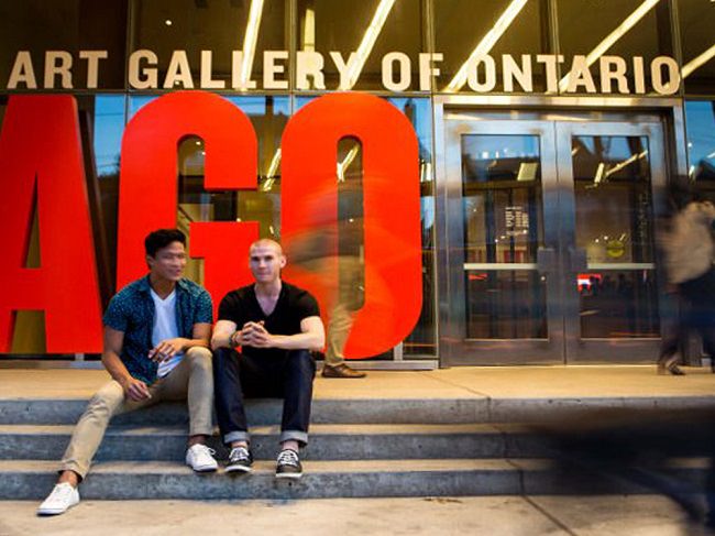 Two men sit on the steps in front of the AGO