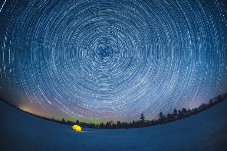 Une tente illuminée sous une spirale d’étoiles.