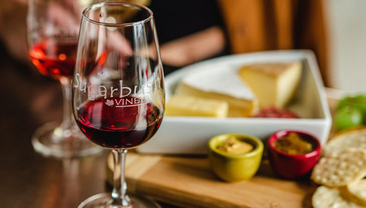 Two glasses of wine and a cheese plate on a table.