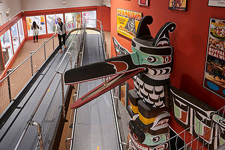 A woman walks by Indigenous art and carvings at Woodland Cultural Centre.